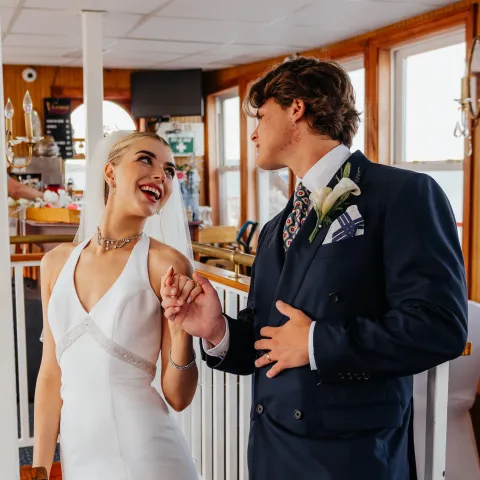 Bride and groom smiling at each other on a staircase.
