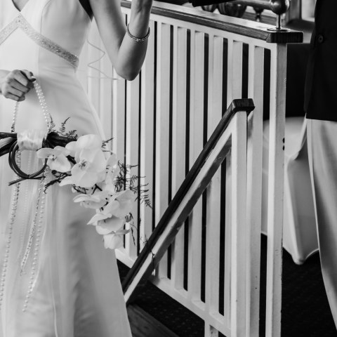 Bride in gown holding hands with a man, holding a bouquet.