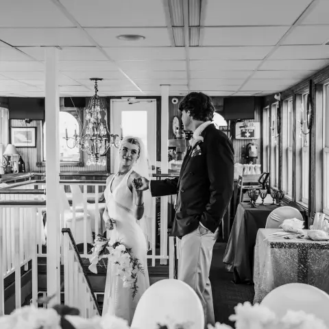 Bride and groom in a decorated room with chandeliers and windows.