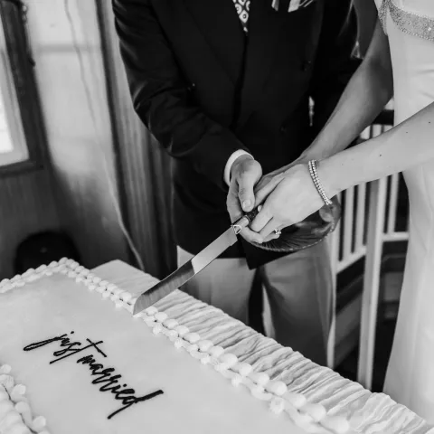 Couple cutting a rectangular cake with 'just married' decoration.