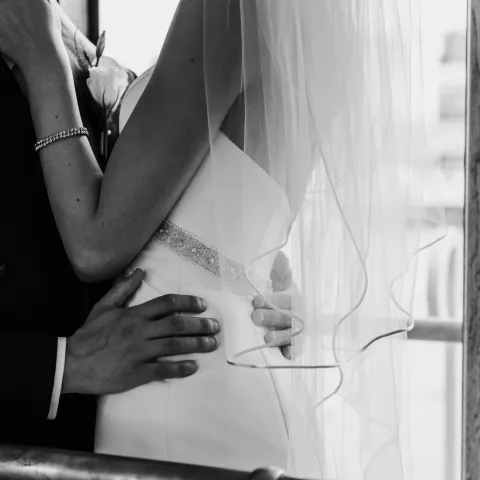 Close-up of a bride and groom embracing, bride wearing a veil.