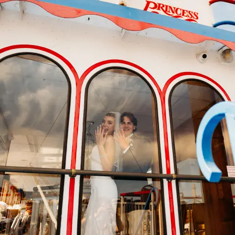 Couple smiling through boat window with 'Victorian Princess' sign above.
