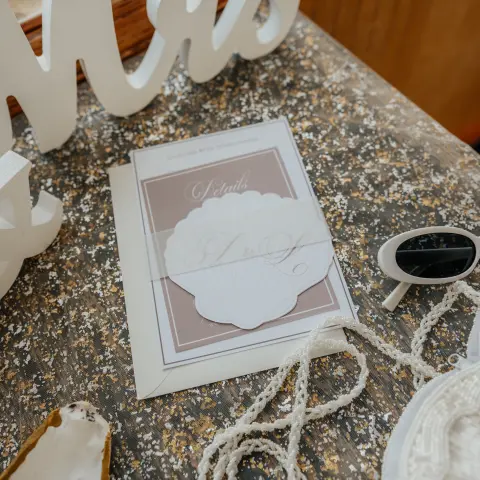 Wedding invitation and decor on a granite countertop with a 'Mrs' sign.