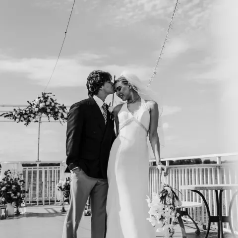 Bride and groom kissing on a decorated outdoor deck.